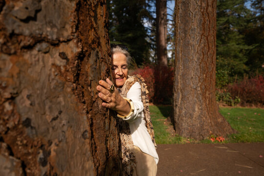 Mujer de la tercera edad abrazando &aacute;rbol grande en oto&ntilde;o