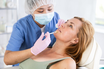 Woman getting procedure of injection contouring and lip augmentation for facial correction in...