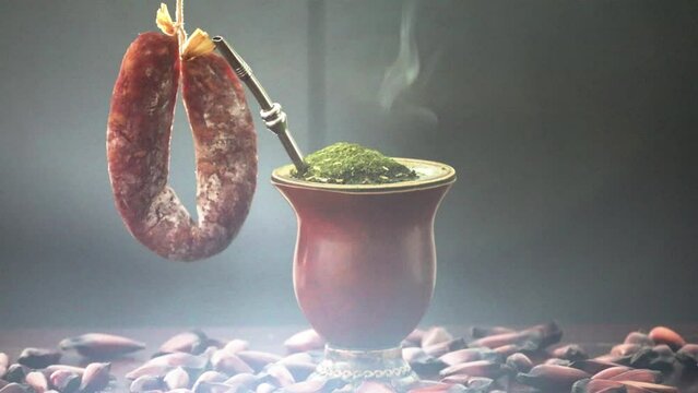 Traditional Brazilian chimarr&atilde;o typical gaucho with yerba mate in a special video with dramatic lighting in a rustic environment with Arauc&aacute;ria pine trees and smoked salami