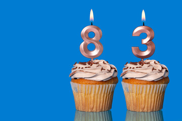 Birthday Cupcakes With Candles Lit Forming The Number 83.