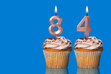 Birthday Cupcakes With Candles Lit Forming The Number 84.