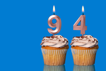 Birthday Cupcakes With Candles Lit Forming The Number 94.