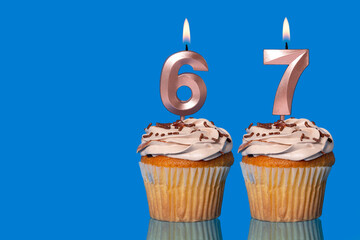 Birthday Cupcakes With Candles Lit Forming The Number 67.