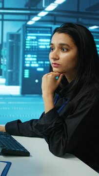 Vertical video IT engineer in data center using PC to find misconfigurations affecting rackmounts performance. Woman checking servers bottlenecks leading to sluggish data transfer rates and