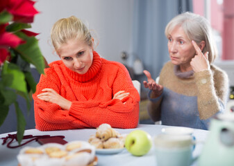Mature woman scolds her adult daughter, who came to visit her before Christmas, pointing out her...