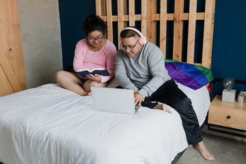 lgbt lesbian latin couple on bed at home in Mexico, Hispanic homosexual people from lgbtq community with rainbow flag in Latin America