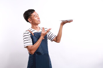 Chef cook holding an empty plate. Portrait of asian chef cook showing plate. Restaurant chef is...