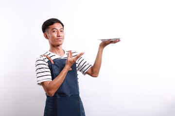 Chef cook holding an empty plate. Portrait of asian chef cook showing plate. Restaurant chef is...