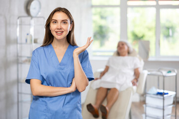 Fototapeta premium Portrait of young female doctor wearing uniform standing in treatment room at beauty clinic