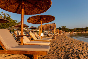 Straw umbrellas and sunbeds on the beach against the background of the sea at dawn. Relaxing...