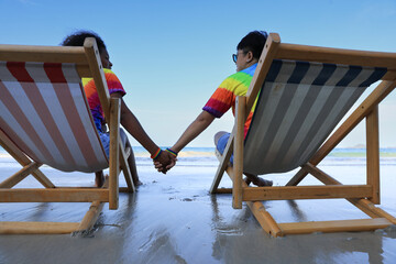 LGBTQ couple having a good time together at the beach. Couple holding hands on beach at...