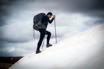 The traveler is engaged in extreme sports, climbs to the top of a snow-covered mountain with...