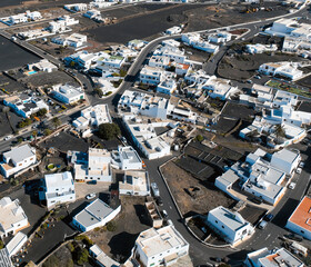 White buildings, town among volcanic black mountains and lava formations in Lanzarote, Canary Islands.
