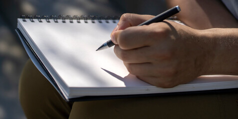 Man is writing notes on a white paper, hands closeup.