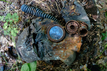 Old worn rotten gas mask lying on grass. Post apocalyptic concept
