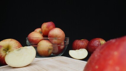 Macrography of apples displayed in various forms: whole, sliced, and within a glass bowl with black...