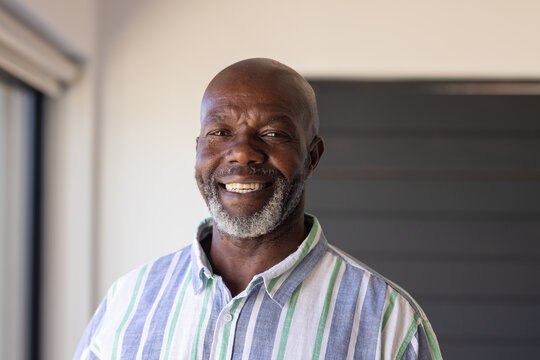 An African American senior male, wearing striped shirt, smiling at home