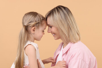 Family portrait of happy mother and daughter on beige background