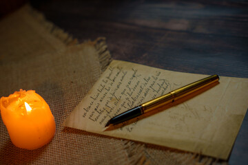 An antique letter with a gold pen in the candlelight