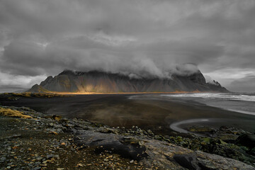 Vestrahorn mountain covered in dark clouds and view of the beach