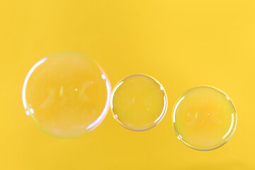 Beautiful transparent soap bubbles on yellow background