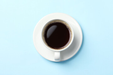 Cup of aromatic coffee on light blue background, top view