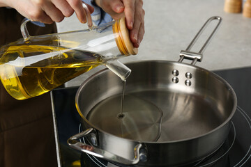 Vegetable fats. Woman pouring cooking oil into frying pan on stove, closeup