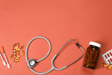 Stethoscope, syringes and pills on crimson background, flat lay. Space for text