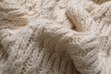 Beige knitted scarf as background, closeup view