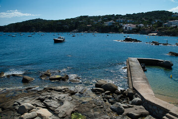 Boats anchored near a rocky cove in Calella de Palafrugell with its small breakwater, a fishing...