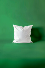 A white pillow sits on a green background
