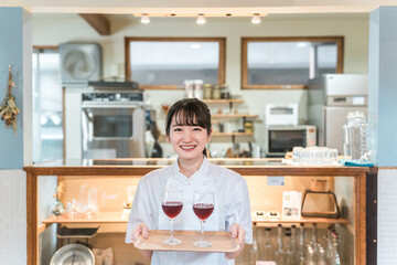 飲食店・バー・居酒屋・ワインバー・バル・ワインショップで赤ワインを持つ女性(ソムリエ・シェフ)
