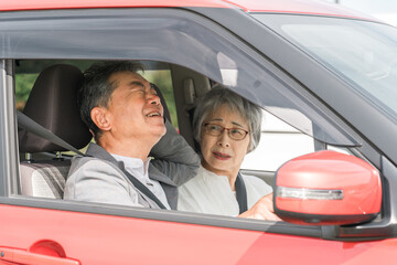 交通事故で鞭打ちの怪我をするドライバーの高齢者夫婦（シニア・男女）
