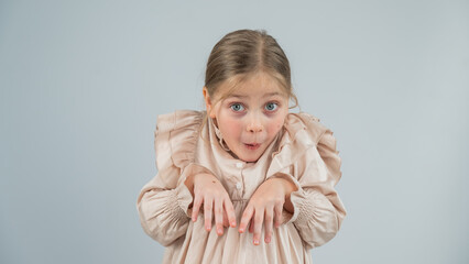 Little Caucasian girl having fun and making faces on a white background. 