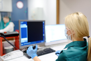 Female radiologist is going to take X ray of patient in X-ray room of modern clinic. Close up photo of doctor hand presses button for execute of medical examination