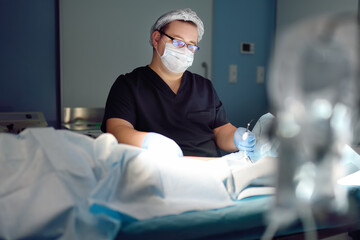 Professional vascular surgeon is in the operating room of the clinic during vein surgery. Phlebectomy. Modern technology of deep vein thrombosis treatment.