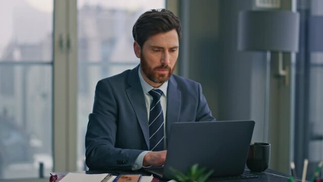 Serious specialist working laptop sitting office closeup. Man typing computer