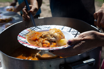Primer plano plato con comida servido por manos solidarias en comedor popular