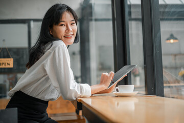 A woman is sitting at a table with a tablet in front of her. She is smiling and she is enjoying her time