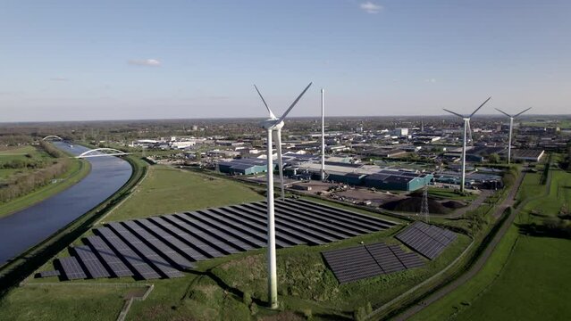 Clean energy wind turbines and solar panels hub in The Netherlands slow aerial pan on a sunny day
