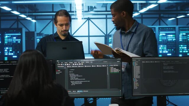 Inspector overseeing server room, reading paperwork and evaluating work done by multiracial team. Supervisor doing inspection in data center, examining hardware performance and workers output