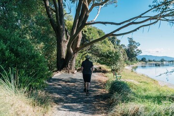 Man walking along tral next to the ocean in  Motueka, Tasman, New Zealand.