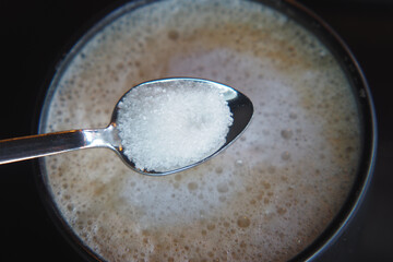  dropping sugar from a spoon in a coffee cup ,