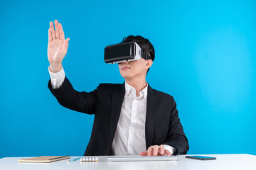 Asian businessman looking through VR connecting touchscreen hologram monitor in futuristic...