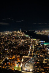 Manhattan's night skyline from a daring perspective from above. Towering giants pierce the clouds, offering a unique vantage point for travel and architecture content. Buildings with lights on.