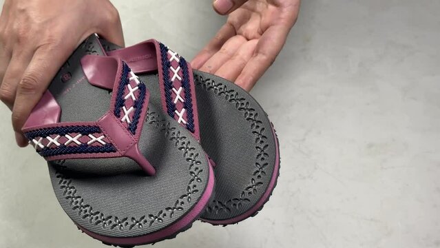 Close-up view 4k stock video footage of new pair of soft and flexible eva slippers in hands of woman