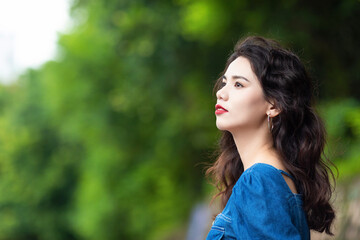 Outdoors a curly-haired Chinese beauty in a denim skirt