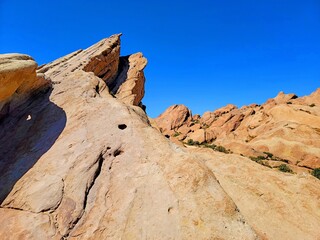 Vasquez Rocks. Jagged rock formations extend under a bright blue sky, offering a glimpse of the rugged beauty of a desert landscape.