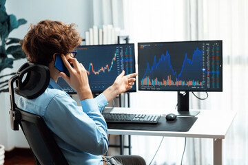 Young investor stock trader calling on smartphone to broker, discussing with dynamic financial...