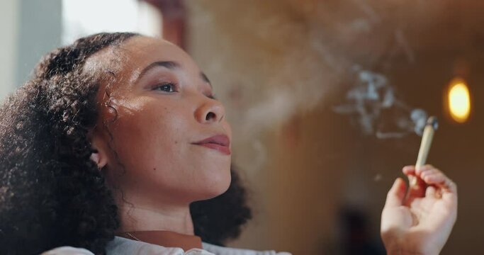 African woman, joint and smoking weed for relax in house or apartment for pleasure with stress relief. Weekend, 420 and cannabis with hemp or natural cbd with drug abuse, danger or enjoying marijuana